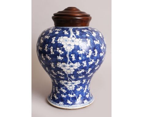 A LARGE CHINESE KANGXI PERIOD PORCELAIN JAR, circa 1700, together with a fitted wood cover, the sides painted with prunus blo