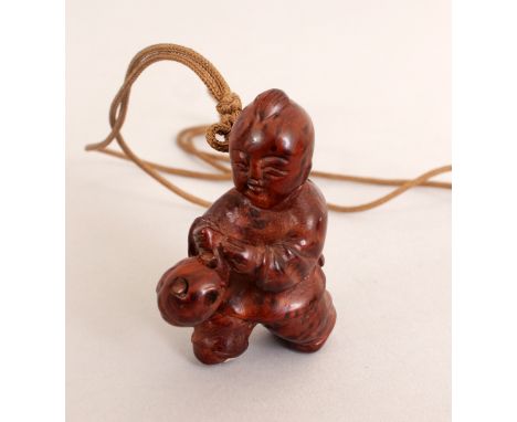 AN EARLY 20TH CENTURY JAPANESE CARVED WOOD NETSUKE OF A CHINESE BOY, running and holding a fish, 1.8in high.