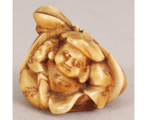 A SIGNED JAPANESE MEIJI PERIOD STAINED IVORY NETSUKE OF DAIKOKU, seated on an enveloping bag, the base with an engraved signa