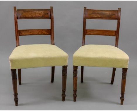 A pair of Regency mahogany ebony banded dining chairs, with curved panelled top rails and bar backs, stuff over seats, on rin