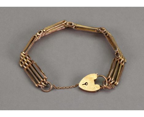 A yellow precious metal fancy four-bar gate-link bracelet, suspending a heart shaped locket and safety chain, 13.5g.