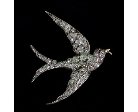 A diamond set brooch designed as a swallow in flight, set throughout with old mine-cut diamonds, with a ruby cabochon eye, se