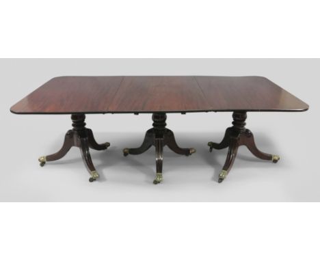 A George III mahogany three pillar dining table, the rectangular top with rounded corners and two extra leaves, on baluster a