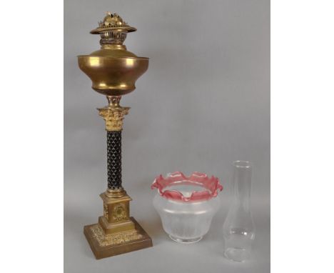 A late Victorian gilt metal oil lamp, with carved ebonised column, on a wreath decorated square pillar and stepped square bas