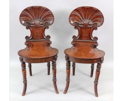 A pair of Regency mahogany hall chairs, in the manner of Gillows, the scallop shell carved backs above 'c' scrolls, the 'c' s