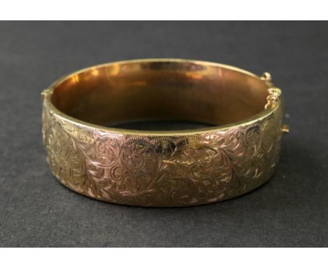 A 9ct gold hinged bangle,of rounded hollow design, engraved with a scrolling leaf design, Birmingham 1917, 25.3g.