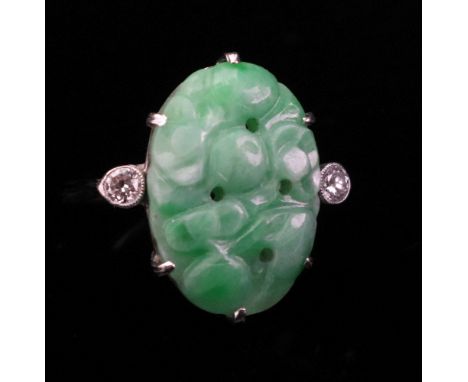A pierced and carved jadeite and diamond-set plaque ring of oval shape, claw-set to a white precious metal mount, set with ci