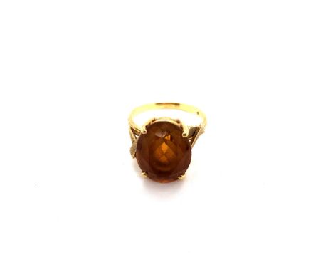 A VINTAGE OVAL ORANGE CITRINE GEMSET RING IN A RAISED FOUR CLAW SETTING. THE SHANK UNHALLMARKED WITH AN INDISTINCT MAKERS MAR