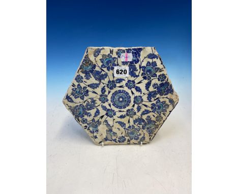 AN EARLY HEXAGONAL IZNIK TILE DECORATED IN BLUE, TURQUOISE AND BLACK WITH VINES FLOWERING AROUND THE CENTRAL ROSETTE. W 23cms