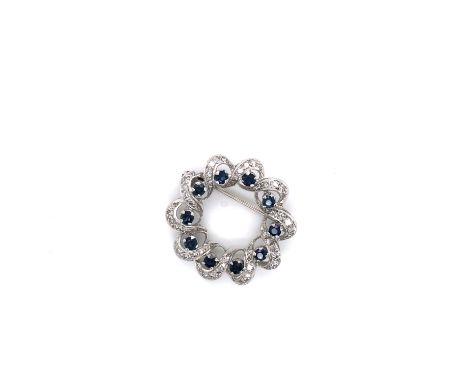 A SAPPHIRE AND DIAMOND FLUTED WREATH BROOCH. THE BROOCH SET WITH TEN ROUND BRILLIANT SAPPHIRES IN FOUR CLAW SETTINGS, IN A WR