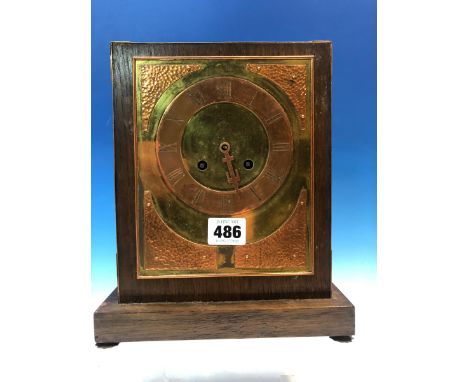 AN ARTS AND CRAFTS MANTLE CLOCK STRIKING ON A BELL, THE BRASS DIAL WITH COPPER CHAPTER RING AND HAMMERED SPANDRELS.   24 x 20