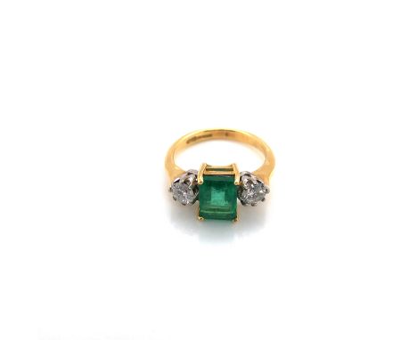 AN 18ct YELLOW GOLD HALLMARKED EMERALD AND DIAMOND RING. THE RECTANGLE CUT EMERALD APPROX MEASURMENTS 8 x 6.1mm, FLANKED BY R