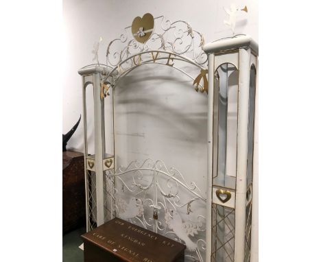 A WHITE AND GILT METAL GARDEN BOWER GATE, THE ARCH INSCRIBED LOVE SUPPORTED ON COLUMNS DECORATED WITH HEARTS AND TOPPED BY TR