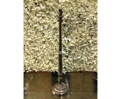 A SILVERED METAL CANDLESTICK TABLE LAMP, THE GUN BARREL COLUMN FLARING TO THE LEAF DECORATED CIRCULAR FOOT.   H 69cms.