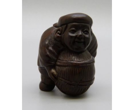 An iron wood netsuke, man with barrel 