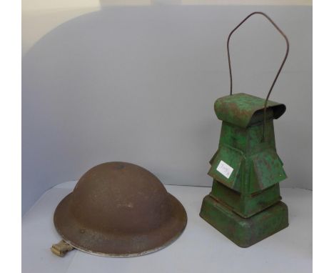 A WWII paraffin black out lamp with original burner and wick and a WWII British helmet with liner and strap 