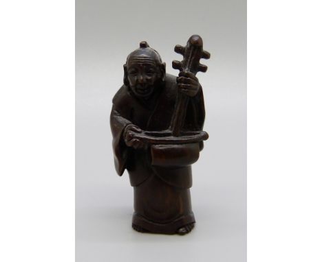 An iron wood netsuke, man with musical instrument 