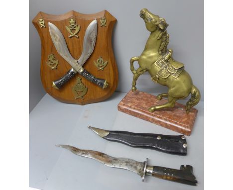 A pair of mounted kukri on a wooden plaque, a Malaysian kris and scabbard and a brass model of a rearing horse on a stone pli