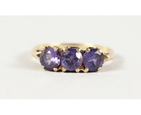 A 10K YELLOW GOLD THREE-STONE AMETHYST RING.