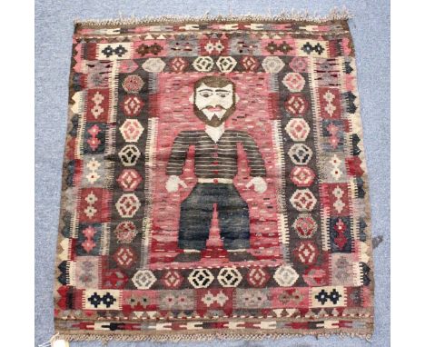 AN UNUSUAL SMALL FLATWEAVE KELIM RUG, the central panel depicting a standing male figure. 3ft 4ins x 3ft 1ins.