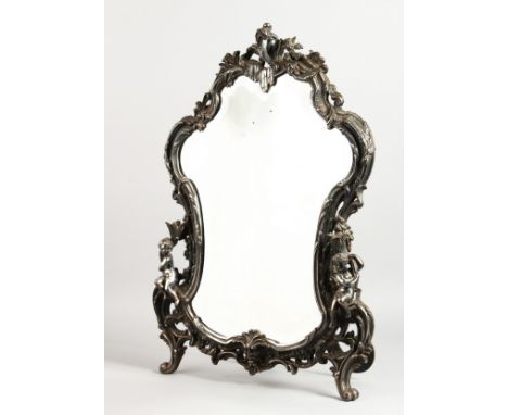 A GOOD, LARGE, SILVER PLATED EASEL MIRROR, rococo style, mounted with cherubs. 24ins high x 17ins wide.