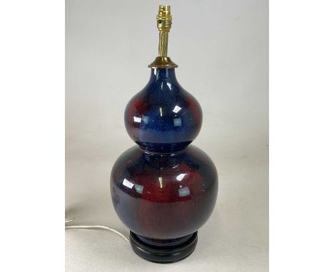 A blue and red glazed ceramic double gourd table lamp base mounted on an ebonised circular wooden plinth, height 47cm.