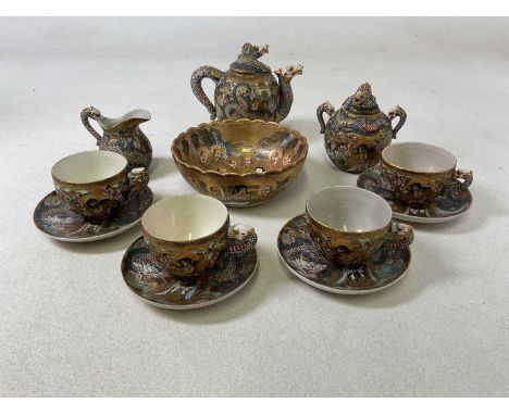 A Japanese late Meiji period Satsuma part tea set comprising teapot, twin handled sugar bowl and cover, jug, four cups, four 