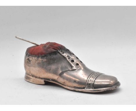 A George V hallmarked silver novelty pin cushion modelled as a shoe, with oak base, Birmingham 1910, length 12.5cm.