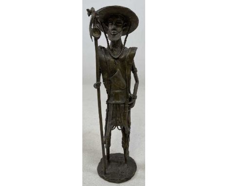 A Tanzanian bronze figure of a warrior, standing wearing hat and holding a staff, height 41cm.