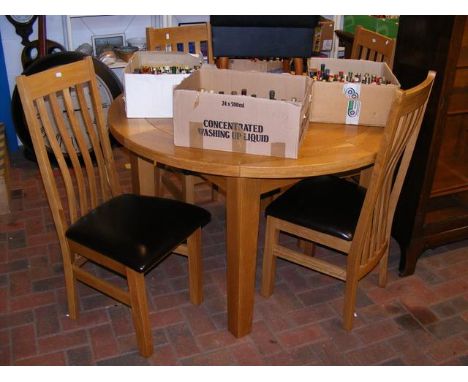 A contemporary light oak extending dining table (125cm in diameter when NOT extended), together with four slat back chairs 