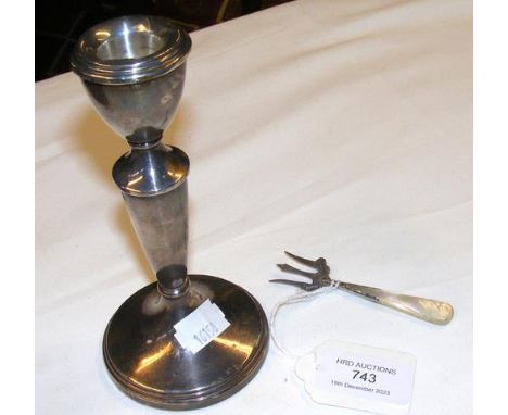 A silver candlestick together with a pickle fork