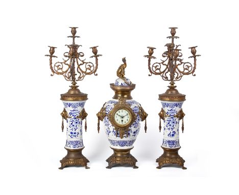 A FRENCH GILT METAL MOUNTED BLUE AND WHITE CLOCK GARNITURE
Late 19th Century
The clock with lion mask drop ring handles and d