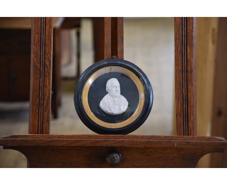 A 19th century wax relief portrait of a portly gentleman on a black background with gilt slip, convex glass and ebonised circ