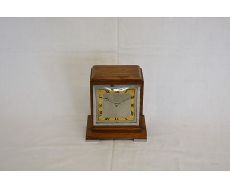 An Art Deco style walnut mantel clock, the silvered dial with gilt chapter ring and black roman numerals with retailers name 