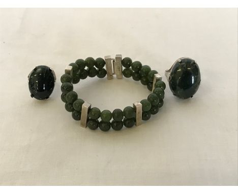 A jade bead bracelet formed from two strings interspersed by white metal bars and two silver mounted jade rings.  Est £30-50