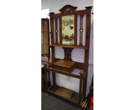 An Art Nouveau oak hall stand, shaped and pierced pediment, mirror, hooks and shelf to top, glove box and stick stand to base