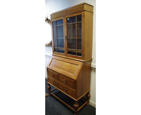 A 1920/30's light oak bureau bookcase, blind fretworked frieze, two glazed doors enclosing shelving to top, fall front enclos