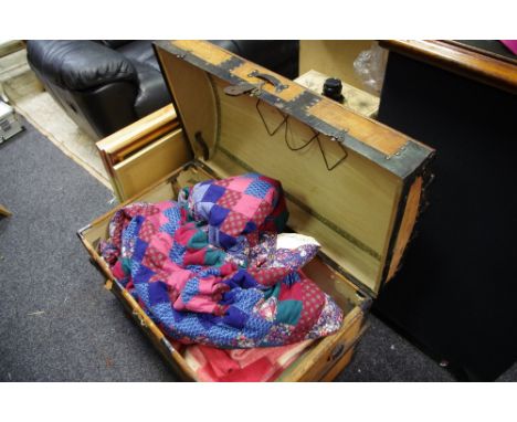 A wooden metal bound dome top trunk, patchwork quilt, other textiles.