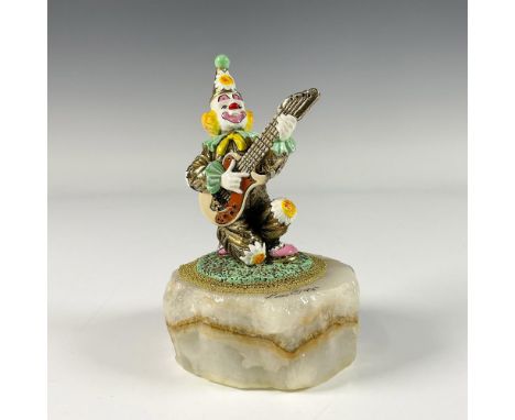 A gilded enamel figure of a cheerful clown playing an electric guitar. Presented on a white onyx stone base. Artists signatur