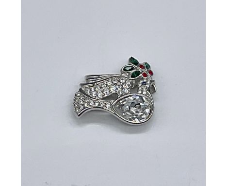 Rhodium plated dove is holding a holly branch in its mouth. The dove is adorned with clear crystals, while the holly branch i