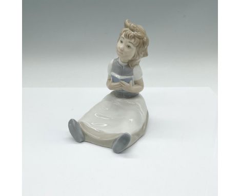 High glazed figure of a young girl seated on the floor with a book in her hands. Nao backstamp. Series number: 246G/M. Artist