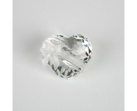 A clear faceted figure of a round heart adorned with a matte ribbon. Part of the Exquisite Accents series. Swarovski marking.