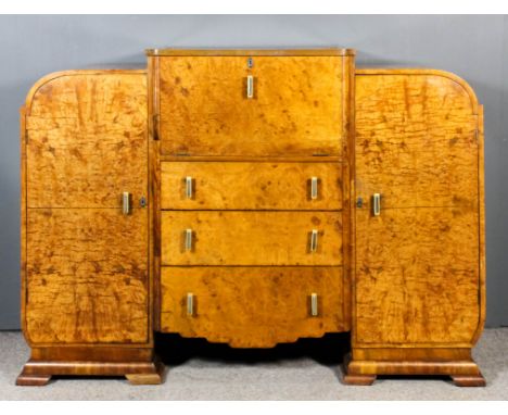 A 1930's figured walnut cocktail cabinet of "Art Deco" design, the central lifting lid and fall front opening to reveal mirro