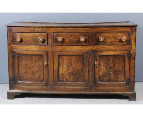 An early 19th Century panelled oak dresser base with plain top, fitted three frieze drawer with turned knob handles, cupboard