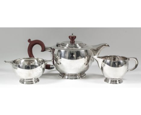 A George V silver circular three-piece tea service of Art Deco design of bulbous form, with scroll handles, on circular mould