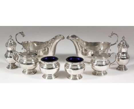 A pair of George VI silver oval sauce boats with cast Celtic pattern rims, high scroll handles with dragon head terminals, on