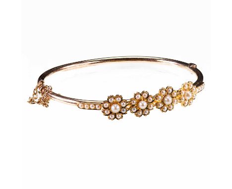 A LATE 19TH CENTURY PEARL HINGED BANGLE unmarked, applied with four pearl set flower heads, and further pearls to shoulders. 