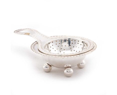 A NEOCLASSICAL-STYLE GERMAN SILVER TEA STRAINER ON STAND each with an anthemion border. (2) 15cm wide across handle, 3.9 troy