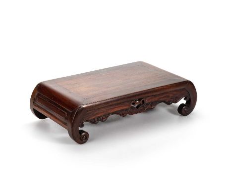 A CHINESE DARK HUANGHUALI TABLE STAND modelled in the form of a miniature kang table with scroll end supports, the frieze cen