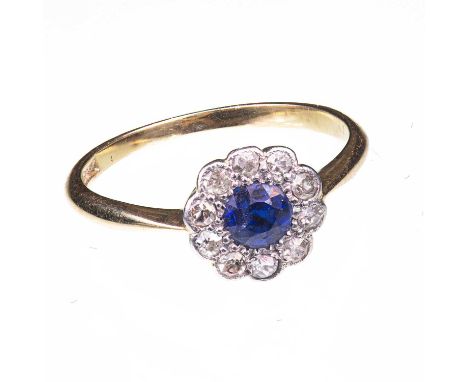 AN EDWARDIAN SAPPHIRE AND DIAMOND FLOWER HEAD CLUSTER RING  marked '18CT', set with a round cut sapphire within a border of d